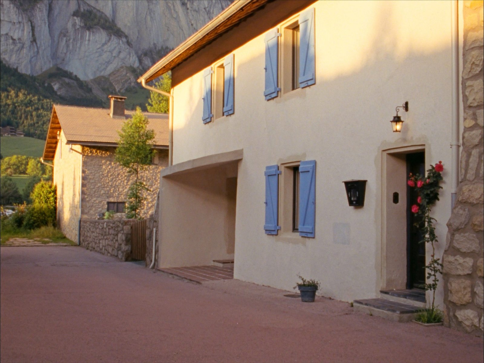 Façade en pierre aux volets bleus de La Maison du Bourg